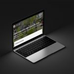 A modern Apple laptop on a grey background showing the University of Dundee website with a high zoom level