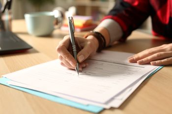 Hand filling in a form on paper